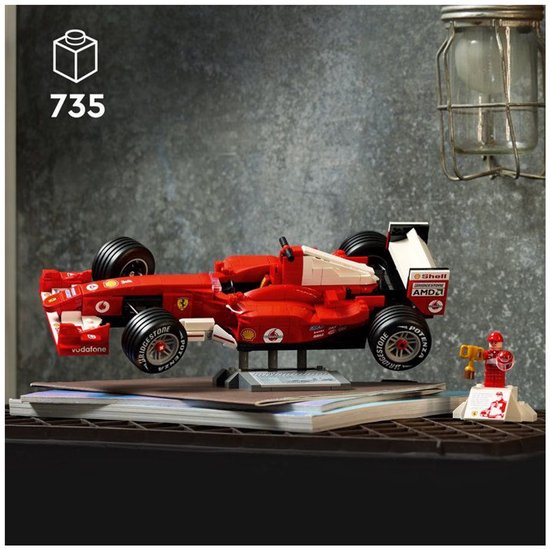 Voiture de course LEGO Ferrari F2004 rouge sur support, à côté d'une figurine de Michael Schumacher.