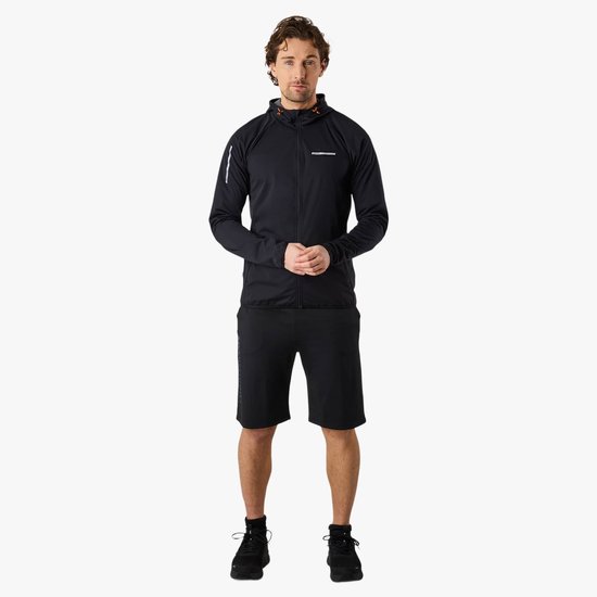 Man staat in een zwarte, lichte hardloopjas met capuchon en korte broek, witte streep op mouw.