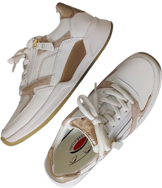 Twee witte sneakers met goudkleurige en taupe accenten, één ligt voor de ander.