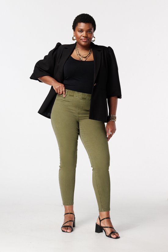 Model met zwarte blazer en groene skinny tregging.