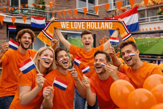 Groep lachende mensen in oranje shirts, sommigen met gezichtsverf, die Nederlandse vlaggetjes en een sjaal met "WE LOVE HOLLAND" vasthouden.