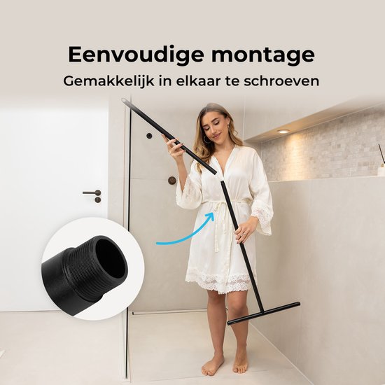 Une femme en robe de chambre monte une raclette de douche noire. Montage facile par vissage.