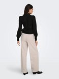 Model met beige wijde broek en zwarte gebreide top, zicht op de achterkant.
