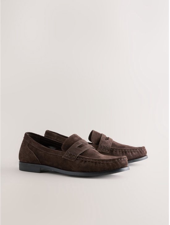 Paar bruine suède loafers met band en stiksels.