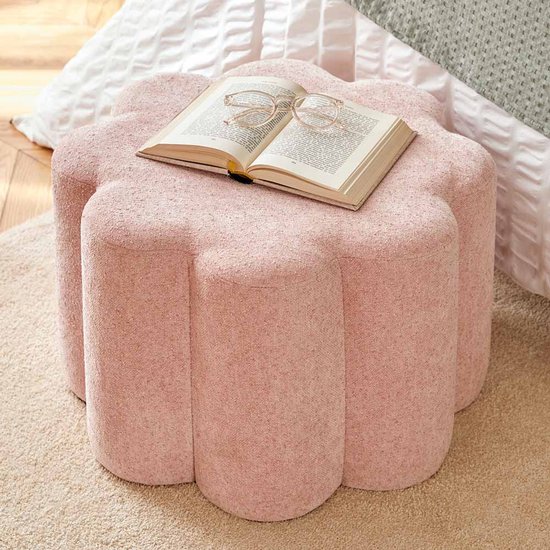 Pouf rose en forme de fleur avec un livre ouvert et des lunettes dessus.