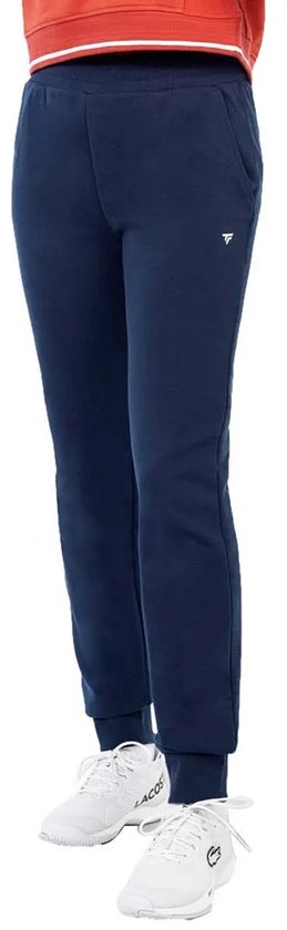 Donkerblauwe Tecnifibre trainingsbroek op een model, met zijzakken, geribde boorden en wit logo.