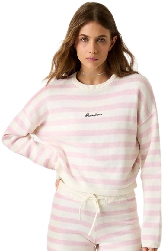 Model draagt roze en witte gestreepte trui en korte broek. Tekst op trui: Guess Jeans.