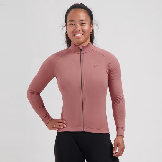 Vrouw van voren gezien, lachend, draagt een oudroze fietsshirt met lange mouwen en rits, met een subtiel logo op de borst.