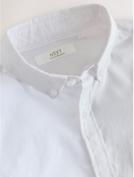 Witte katoenen button-down overhemd, close-up van de kraag met het Next-label.