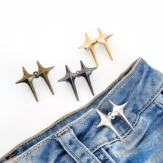 Vier decoratieve sterrenhaakjes in brons, donkergrijs, goudkleurig en zilverkleurig, bevestigd aan jeans.