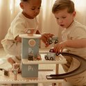 Twee kinderen spelen met een houten parkeergarage, auto's en helikopter.
