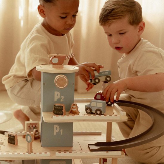 Twee kinderen spelen met een houten parkeergarage, auto's en helikopter.