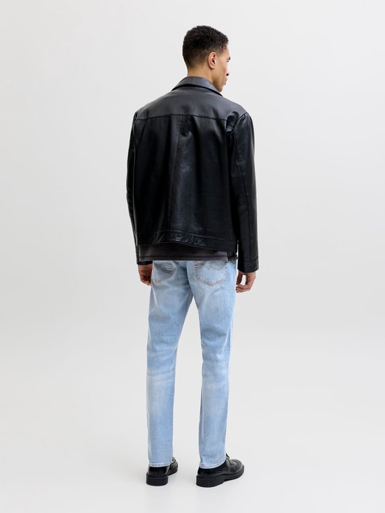 Model van achteren gezien in zwart leren jack en lichtblauwe slim fit jeans.