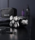 Zwart Remington hoofdscheerapparaat met accessoires, waaronder een tas en handdoek.