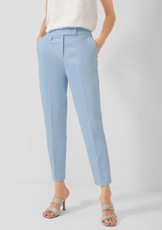 Model draagt een lichtblauwe broek met een witte kanten top.