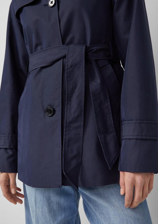 Detail van een donkerblauwe trenchcoat met ceintuur en knoop.