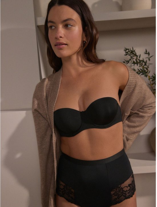Model draagt zwarte push-up beha zonder bandjes en een beige vestje.
