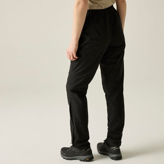 Zicht op de achterkant van een zwarte outdoorbroek gedragen door een model.