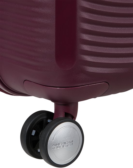 Bordeauxrode koffer met twee zwenkwielen, waarvan één met zilverkleurig American Tourister logo.