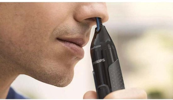 Een man gebruikt een zwarte Philips neustrimmer met blauwe borstelharen in zijn neus.