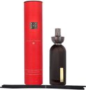 Rode kartonnen verpakking voor 'The Ritual of Ayurveda' geurstokjes, naast een donkere glazen diffuser.