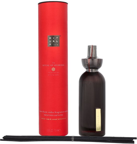 Rode kartonnen verpakking voor 'The Ritual of Ayurveda' geurstokjes, naast een donkere glazen diffuser.