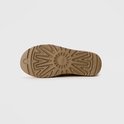 Onderkant van een bruin UGG laarsje met een uitgesproken grof profiel en het UGG logo in het midden.