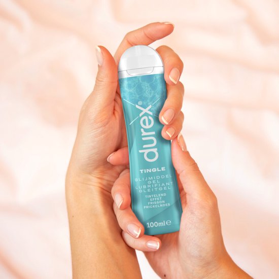 Durex Tingle glijmiddel in lichtblauwe fles met witte dop, vastgehouden in twee handen op een zachte achtergrond.
