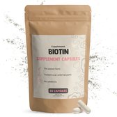 Bruine papieren zak met 60 Biotine supplement capsules. Twee capsules liggen ernaast.
