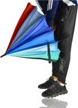 Een persoon met sportbroek kijkt naar een gedeeltelijk gesloten regenboogparaplu met veelkleurige vlakken in blauw, groen en rood.