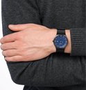 Man met zwart horloge met blauwe wijzerplaat, zilveren indexen en datum. Zwarte Milanese band.
