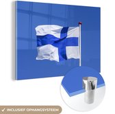 MuchoWow® Glasschilderij 150x100 cm - Schilderij acrylglas - Finse vlag in de blauwe lucht - Foto op glas - Schilderijen