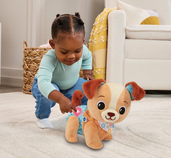 Een baby zit op de grond en speelt met een zachte, bruine puppy met een lichtblauwe broek.