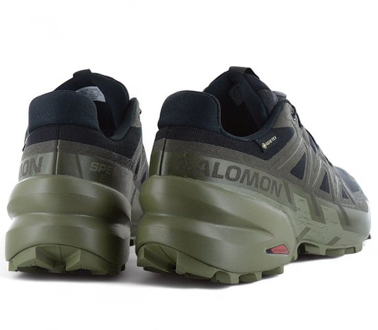 Achterkant van de olijfgroene Salomon trailschoenen met zichtbaar Salomon logo.