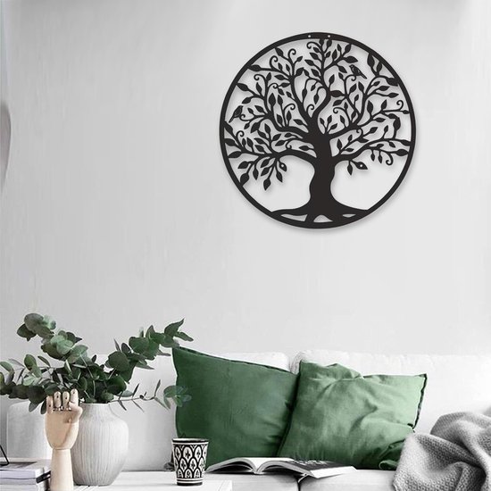 L'arbre de vie en métal noir est suspendu à un mur blanc au-dessus d'un canapé avec des coussins verts.