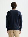 Man met donkerblauwe sweater met ronde hals en beige broek, zichtbaar van achteren.