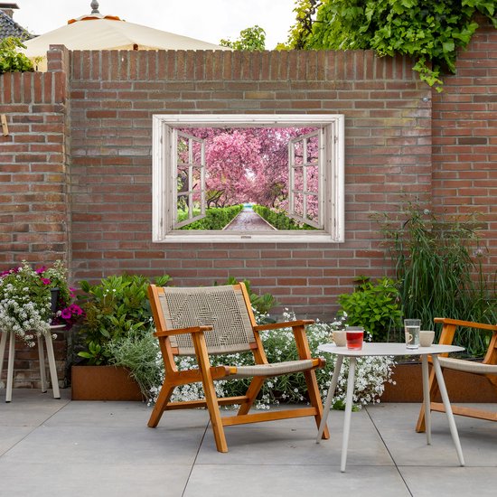 Een schilderij van een open raam met uitzicht op een pad omringd door bloeiende kersenbomen, bevestigd aan een bakstenen muur in een tuin.