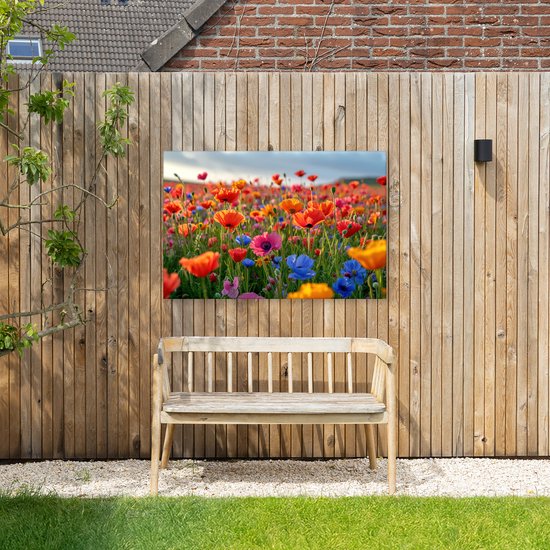 Buitenkunstwerk op doek met een veld vol klaprozen in rood, oranje, blauw en roze, hangend aan een houten schutting.
