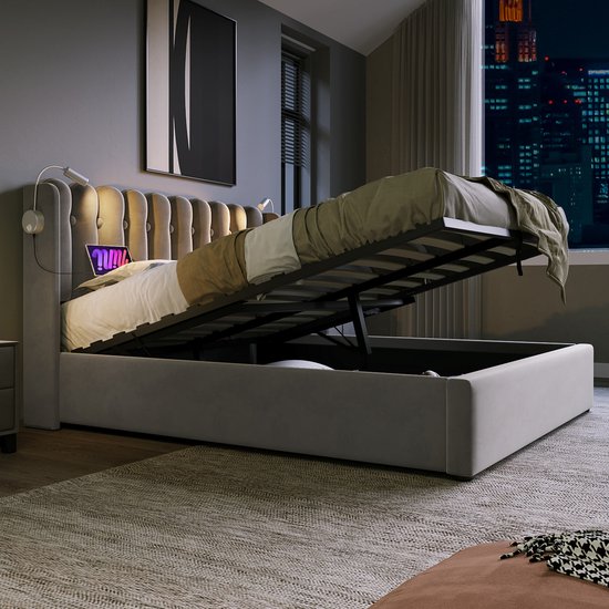 Grijs gestoffeerd bed met opengeklapte lattenbodem in een donkere slaapkamer met uitzicht op de stad.