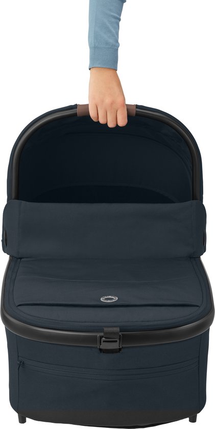 Donkerblauwe reiswieg met bruine handvatten. Een hand pakt de reiswieg vast.