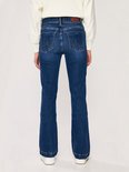 Achterkant van een vrouw in een donkerblauwe flared jeans met een omgeslagen zoom.
