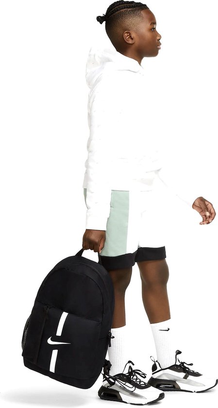 Jongen draagt zwarte Nike rugzak met witte strepen. Hij houdt hem vast aan de zijkant.