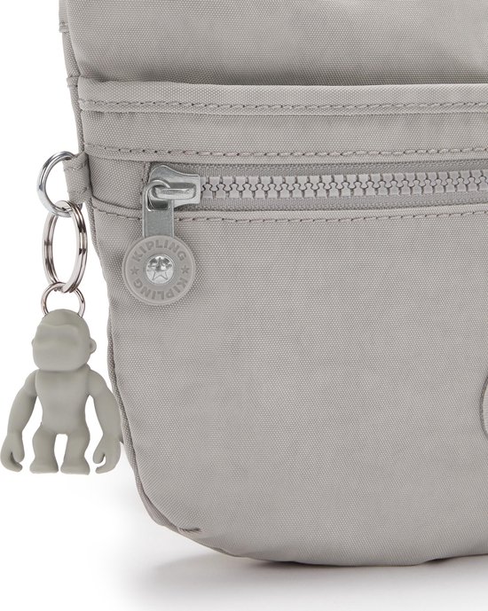 Detail van een lichtgrijze Kipling schoudertas met ritssluiting en Kipling aap sleutelhanger.