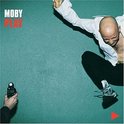Moby Play albumhoes met Moby die in de lucht springt, in een witte blouse en zwarte broek.