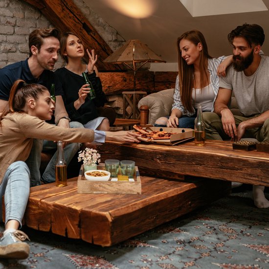 Groep vrienden in een woonkamer, genietend van pizza en drankjes.