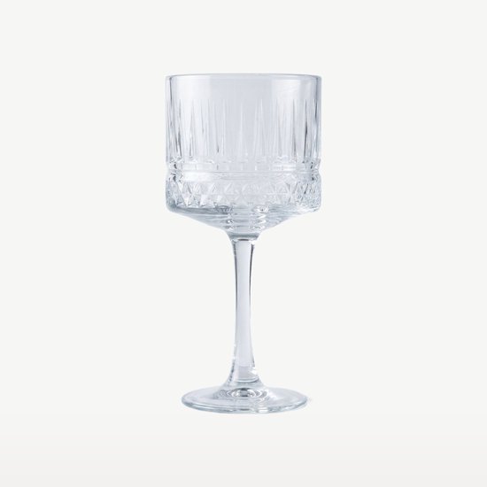 Een hoog cocktailglas met een brede voet, verticale ribbels en een diamantpatroon op de voet.