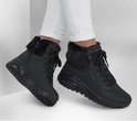 Model draagt zwarte Skechers Uno Rugged veterboots met witte broek, met bontkraag en Air-zool.