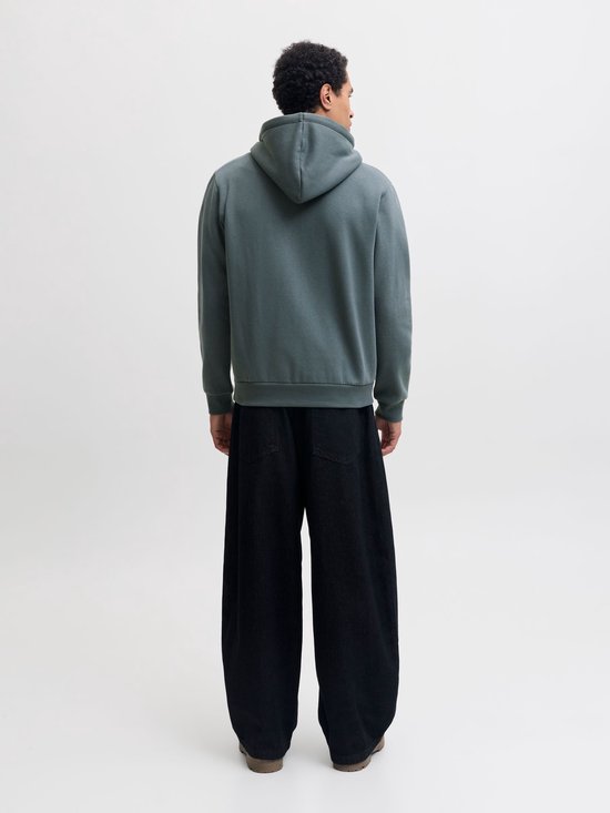 Achterkant van een man in een effen, donkergroene hoodie en zwarte broek.