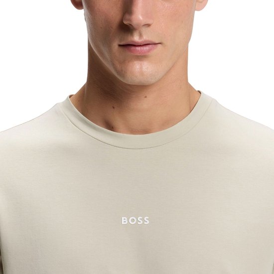Close-up van het bovenlichaam in een beige T-shirt met lange mouwen met het kleine witte BOSS-logo.