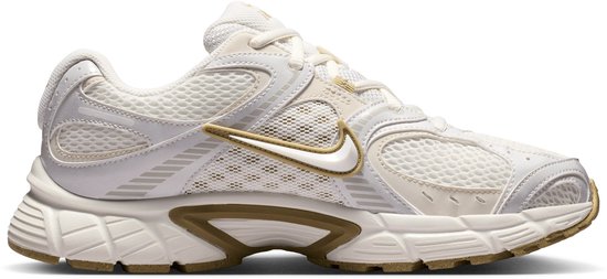 Witte Nike sneakers met beige en gouden accenten. Een goudkleurige Nike swoosh op de zijkant.